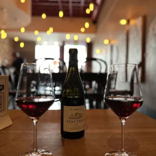 three glasses of wine and a bottle of wine