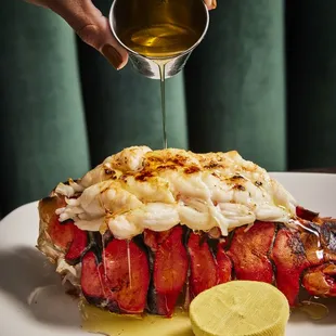a lobster covered in sauce and garnished with a slice of lemon