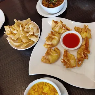 Crab Rangoon a surrounded by egg drop and hot and sour soups.