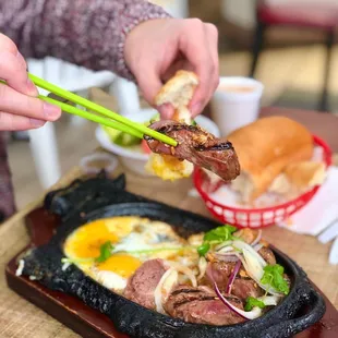 a person holding chopsticks over a plate of food