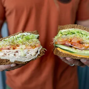 a man holding two sandwiches