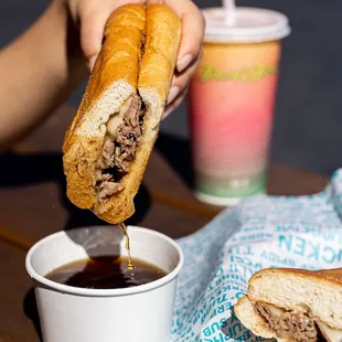 a person dipping a sandwich into a cup of coffee