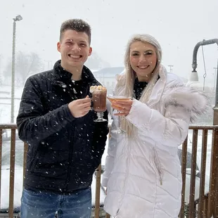 a man and a woman enjoying a drink in the snow