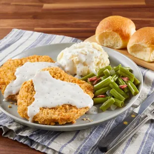a plate of fried chicken with gravy and green beans