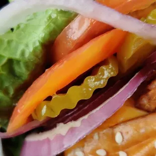 ows a sandwich with lettuce, carrots, onions, and pretzels
