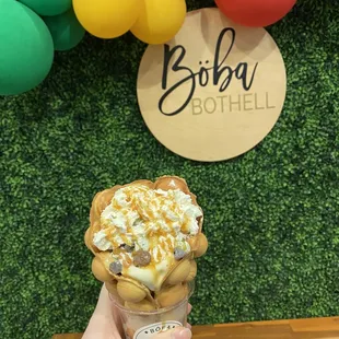 Bubble waffle cone with vanilla ice cream, mochi, chocolate chips, whipped cream and caramel drizzle.