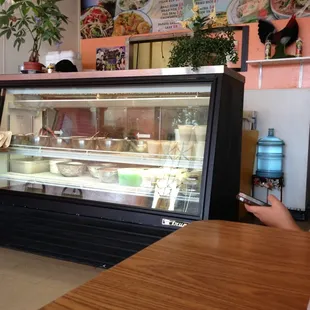 a woman sitting at a table in front of a refridgerator