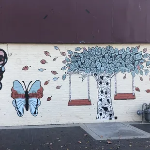 a mural of a tree, a swing, and a butterfly