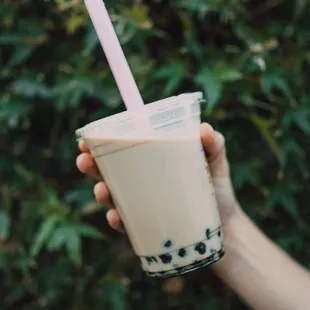 a hand holding a cup of boba
