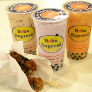 three cups of boba tea and a chicken skewer