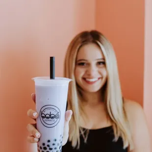a woman holding a cup of boba