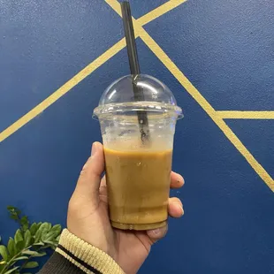 a hand holding a cup of iced coffee
