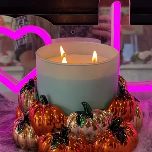 a lit candle surrounded by pumpkins
