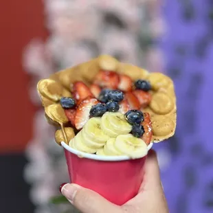 a person holding a cup of fruit