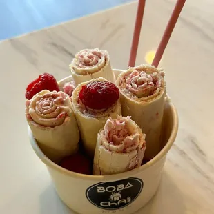 a bowl of strawberries and banana rolls