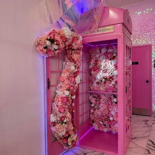 a pink phone booth decorated with flowers