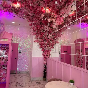 a room with pink walls and flowers hanging from the ceiling