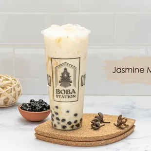 a glass of boba milk tea and a bowl of blackberries