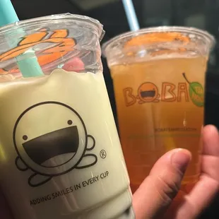 a hand holding two cups of boba tea