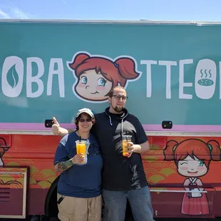 two people standing in front of a food truck