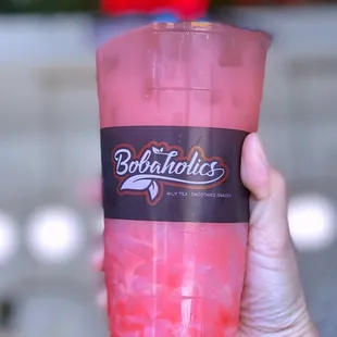 a hand holding a pink drink