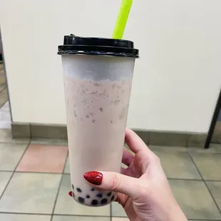 a hand holding a plastic cup with a straw