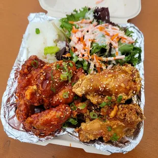a takeout container of chicken wings, rice, salad, and coleslaw