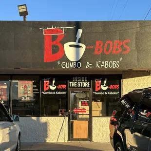 the outside of a restaurant with cars parked in front of it