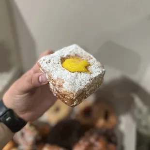 a hand holding a powdered sugared donut