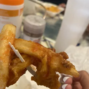 a hand holding a piece of fried food
