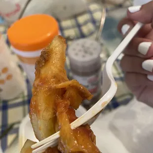 a person holding a fork with a piece of fried food on it