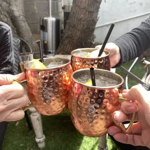 four people holding copper mugs