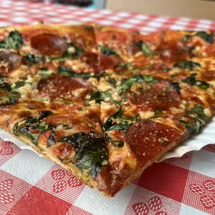 a slice of pepperoni and spinach pizza