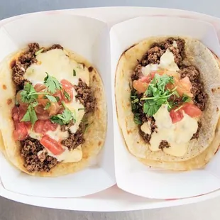 two tacos with cheese and tomatoes