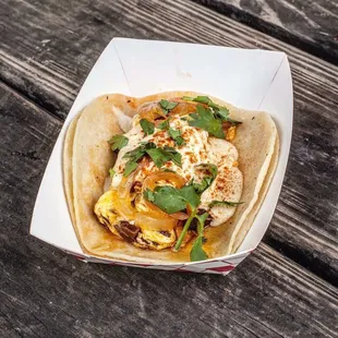 a taco in a paper container on a wooden table