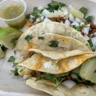 Al pastore tacos with tomatillo salsa and lime wedges