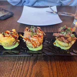 three sushi rolls on a black plate