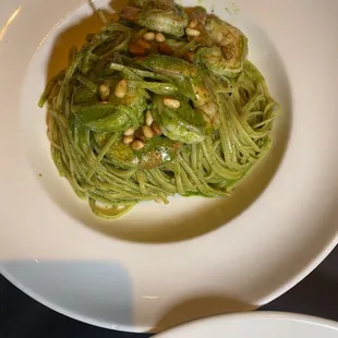 a plate of pasta with pesto and pine nuts