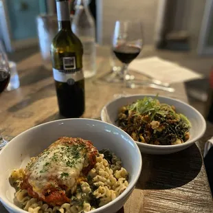 two bowls of pasta and a bottle of wine