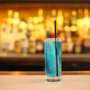 a blue drink with a straw in a tall glass