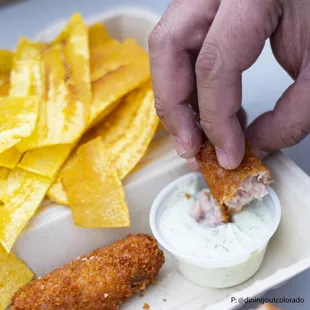 a hand dipping a piece of fish