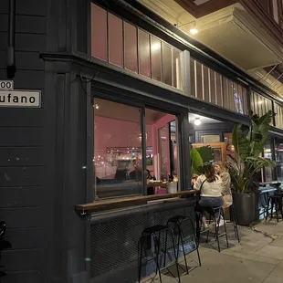 a woman sitting at a table outside of a restaurant