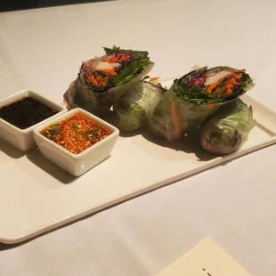 Spring rolls with red chili and black sesame sauces With an old fashion in background. Presentation with smoke and all