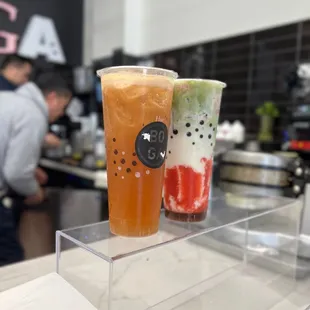 two drinks in plastic cups on a counter