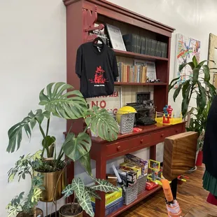 a red bookcase with books and plants
