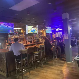 Pool table and bar with drinks and TVs hanging from the ceiling