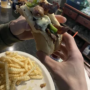 a person holding a sandwich and french fries