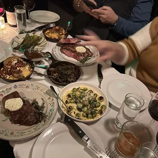 New York Strip, Bone in Ribeye, baked potatoes, Brussels, asparagus and cocktails