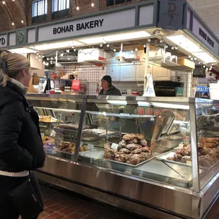 a woman standing in front of a bakery counter