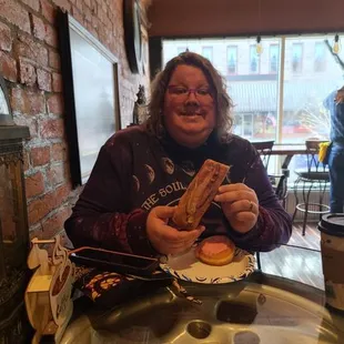 a woman sitting at a table eating a donut